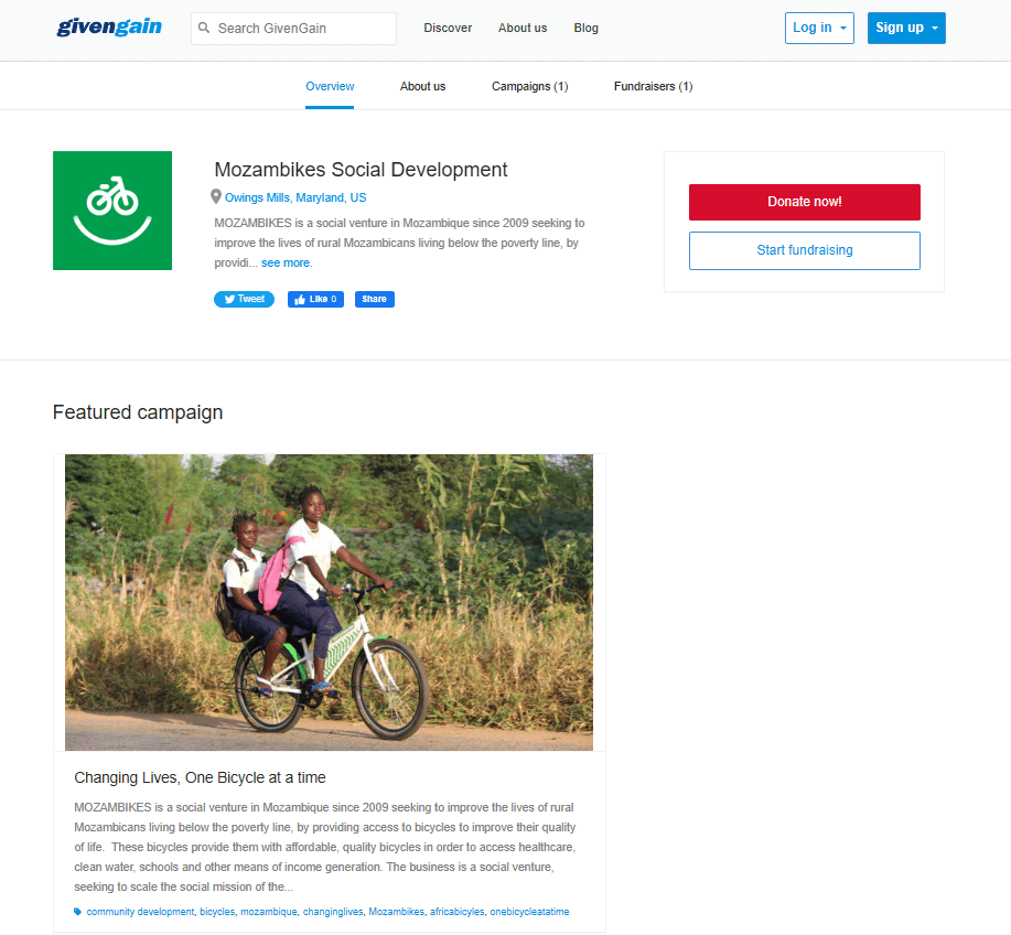 A screenshot of the GivenGain website, featuring a green logo with a white ‘G’ and a navigation bar with options such as ‘Home’, ‘About Us’, and ‘Campaigns’. The main content is a featured campaign called ‘Mozambikes’, with a photo of a person riding a bicycle on a dirt road and a description stating that Mozambikes brings new, affordable bicycles to communities in Mozambique to improve access to healthcare, education, water, food, and economic opportunities. The website also has a ‘Donate now’ button and a footer with options such as ‘Terms of use’ and ‘Privacy policy’.